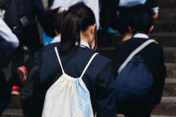 Group of school children students outdoor excursion, guided tour in the city with guide, docent with tourist pupils visitors, wear color caps hats, kids class field trip, urban sightseeing in Japan