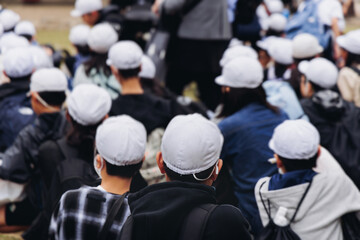 Group of school children students outdoor excursion, guided tour in the city with guide, docent with tourist pupils visitors, wear color caps hats, kids class field trip, urban sightseeing in Japan