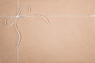 White String Twine Tied in Bow on Kraft Paper Background