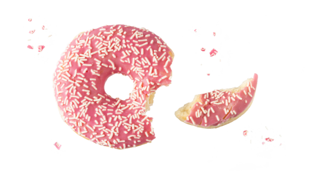 Pink glazed single bitten donut with white sprinkles and crumbs flying isolated on white