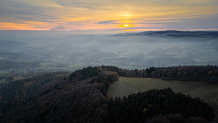 Golden sunset fades into dusk above the Bavarian Forest with fog and mild evening temperatures over Straubing Bogen valleys in autumn Bavaria