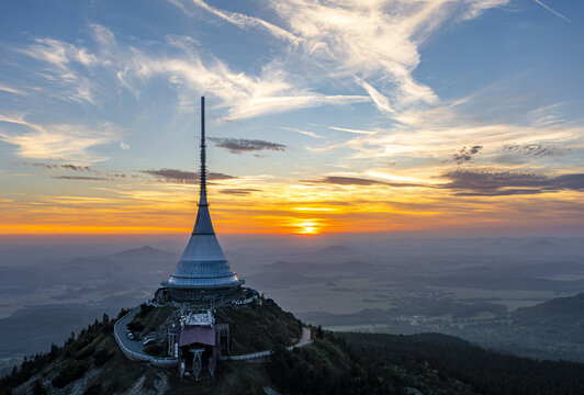 Aerial view of the iconic Jestěd tower piercing the horizon at sunset, its futuristic silhouette a beacon against the vibrant sky, Liberec, Liberecky kraj, Czechia.