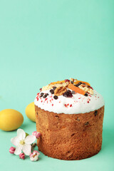 Traditional easter cakes with colorful sprinkles, with eggs and spring flowers on mint background.