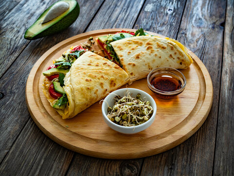 Healthy breakfast - italian piada wraps with scrambled eggs, tomatoes, avocado, coriander and bean sprouts