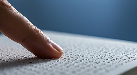Finger reads braille text on white page in closeup, emphasizing accessibility and inclusivity for visually impaired individuals in educational setting.