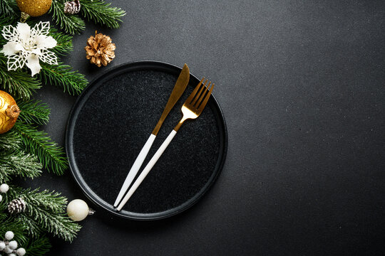 Christmas table setting, food background. Craft plate with golden Christmas decorations and cutlery. Luxury design.