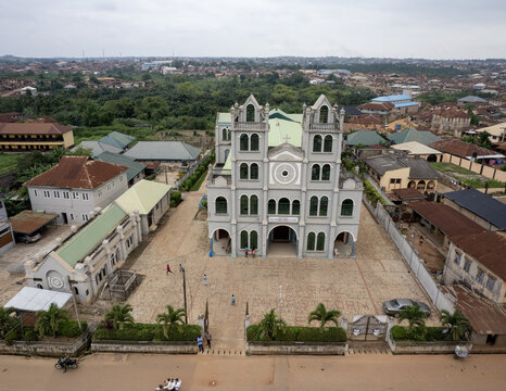 Aerial view of a grand cathedral, its facade a symphony of gray stone, standing proudly amidst a tapestry of buildings and lush greenery, Ifofin, Ilesa, Nigeria.