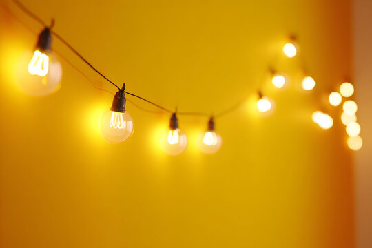 Warm glowing fairy lights on a yellow background for cozy ambiance and decoration