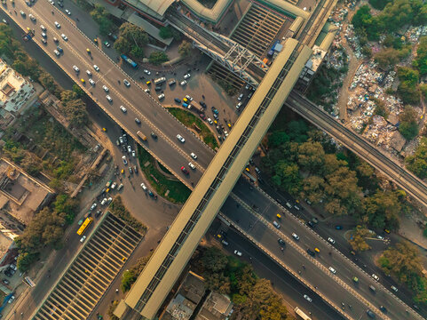Aerial view of a bustling intersection beneath elevated metro lines, where vehicles stream across the roads, offering a glimpse into the vibrant urban landscape of the city, New Delhi, Delhi, India.