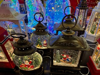 Christmas lanterns designed as illuminated snow globes, displaying santa claus, reindeer, and festive winter scenes among falling glitter, creating a joyful holiday atmosphere