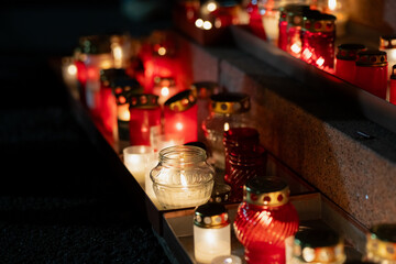 Warm tribute candles in red and white lanterns arranged along Krastmala stone tiers for Lāčplēša Day, highlighting reflective glass textures, layered composition