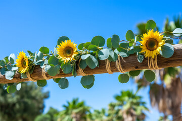 Wooden arch with simple, natural decorations like eucalyptus leaves and sunflowers for a rustic wedding