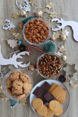 Various Christmas decorations, cookies, chocolate and nuts on wooden background. Flat lay.
