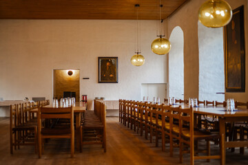 Majestic medieval castle banquet hall with long wooden tables, chandeliers, and stone walls illuminated by warm candlelight, evoking the atmosphere of royal feasts.