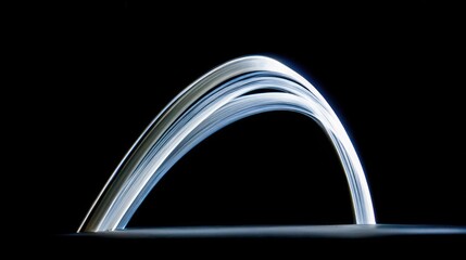 Fototapeta premium Light painting creates an abstract luminous arc against a dark background.