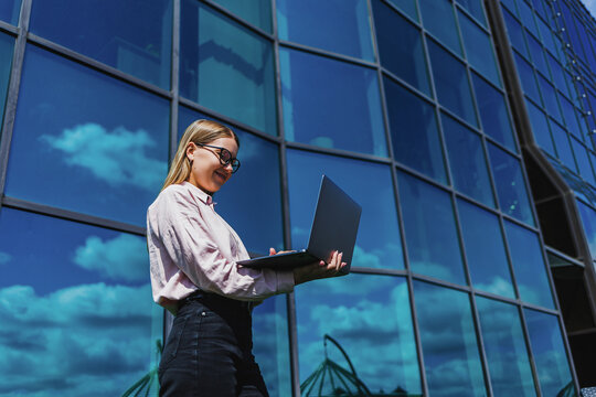 Professionals engage with technology against a striking glass backdrop on a sunny day in an urban environment