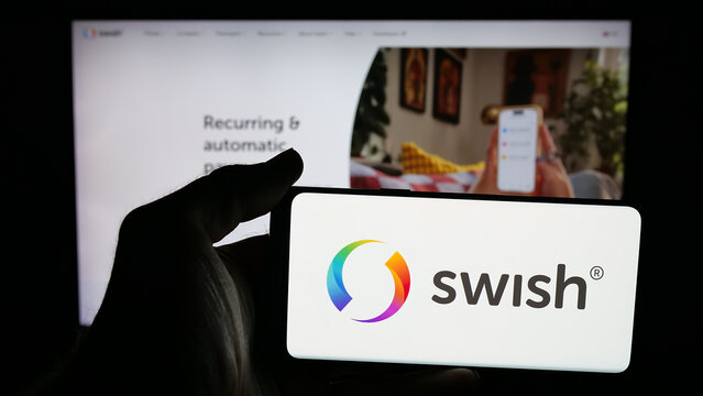 Stuttgart, Germany - 11-03-2025: Person holding mobile phone with logo of Swedish fintech company Swish (Getswish AB) on screen in front of web page. Focus on phone display.