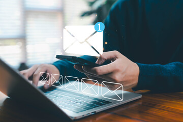 A person checking email notifications on a smartphone and laptop, showing digital communication, messaging alerts, online inbox management, workflow efficiency, and modern connectivity in daily work