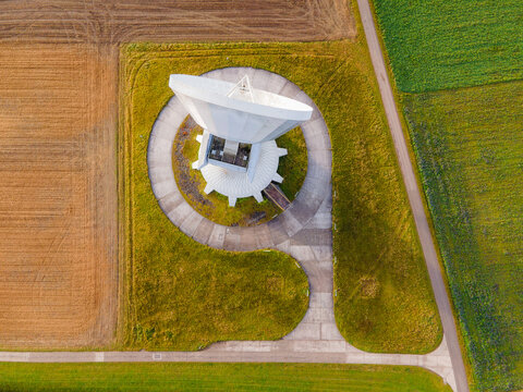 Aerial view of the gleaming Raisting Earth Station antenna, its concrete and metal contrasting with the autumnal fields, Raisting, Bayern, Germany.