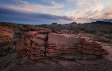 The bizarre pink cliffs of Bektau Ata at sunset. The evening light colors the ancient volcanic formations in warm tones, creating a mystical landscape in the middle of the endless Kazakh steppe.