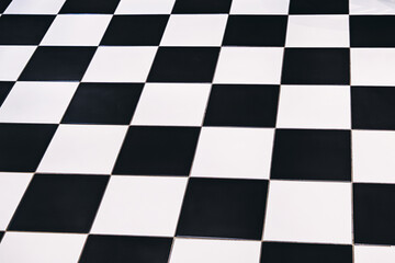 Fototapeta premium Checkered floor pattern with black and white tiles creating a geometric, abstract background with strong perspective