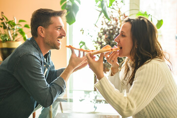 Loving couple shares tender moment in modern kitchen, enjoying pizza