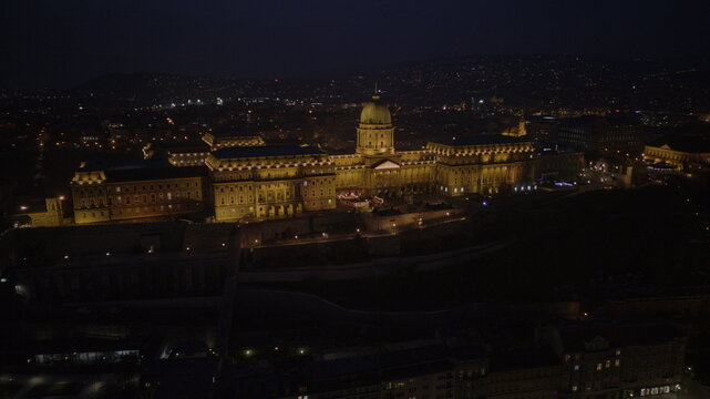 Aerial view of the illuminated Buda Castle shimmers against the inky sky, a beacon of history and majesty overlooking the dark cityscape, Budapest, Hungary.