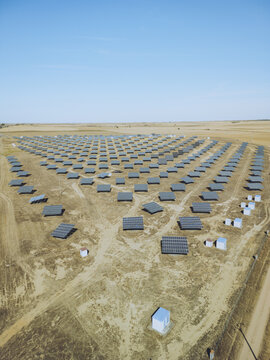 Aerial view of solar panels arrayed in neat rows across the arid landscape, contrasting with the bright blue sky, Uruena, Castile and Leon, Spain.