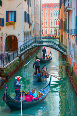Three venetian gondolier punting gondola through green canal waters of Venice Italy © muratart