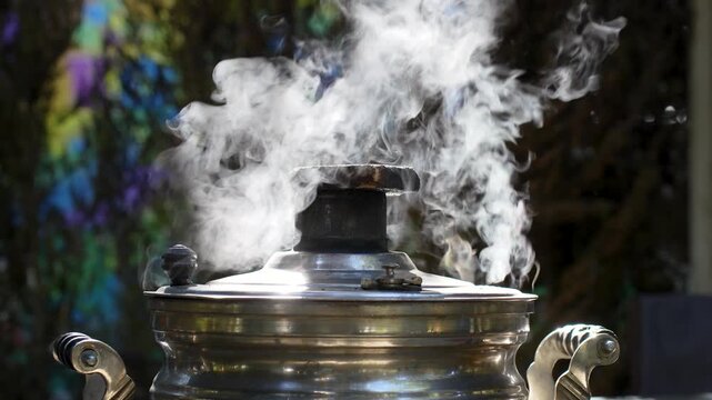 Steaming traditional metal samovar boiling water outdoors in nature