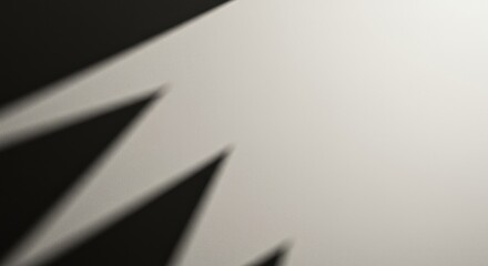 Geometric sharp shadow pattern on a rough pale surface creating a high contrast monochrome minimalist composition with ample negative space ,negative space ,geometry ,design