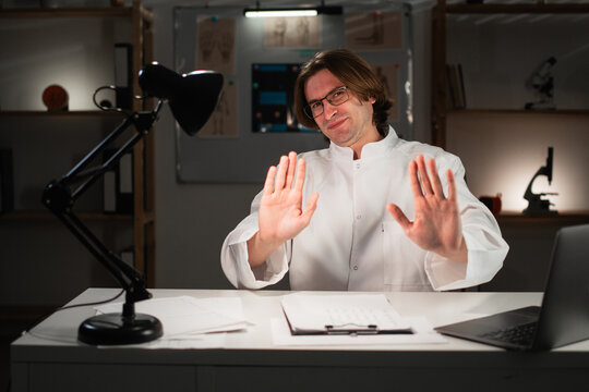 No thank you. General practitioner doctor in eyeglasses shows block, stop gesture, refusing smth while working late night in hospital office