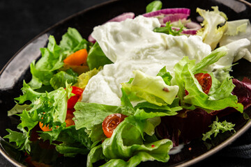 Burrata salad tomato, purple onion, green leaf lettuce tasty snack fresh gourmet food table setting rustic food top view copy space keto and paleo diet vegetarian food