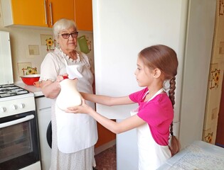 The grandmother passes the girl a pitcher of milk.
