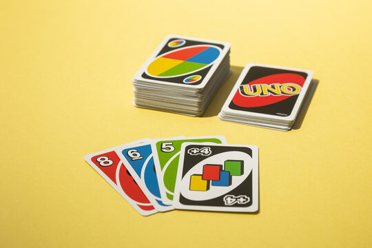 Lisbon, Portugal - 2025-11-13 UNO card game on a yellow background showing stacks and fanned-out cards from the popular family game. Bright and playful composition leisure and entertainment.