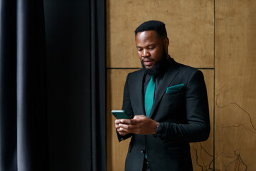 successful African businessman in a black suit with a mobile phone