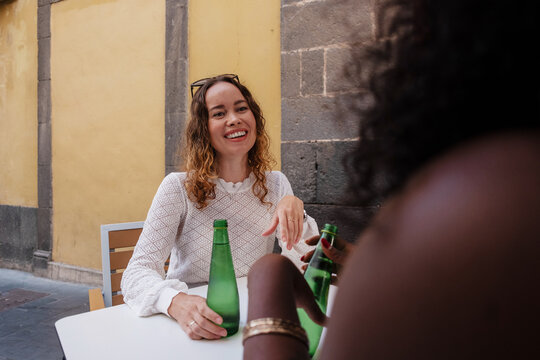 Two happy women friends talking smiling at outdoor cafe