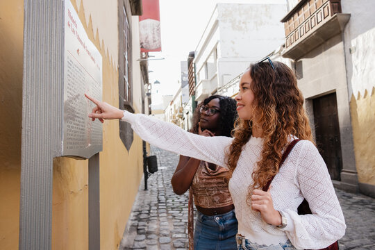 Young women exploring old city street with historic sign