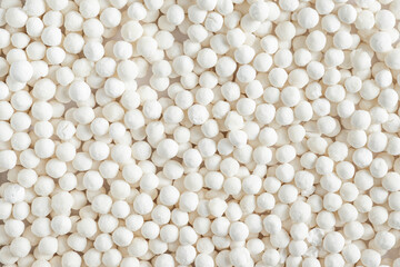 Organic tapioca pearls background. Texture of white dry tapioca pearls, cooking ingredient, gluten-free food, healthy eating.