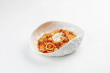 Spaghetti in rich tomato sauce with tender meat pieces, topped with grated cheese and served in a white ceramic bowl