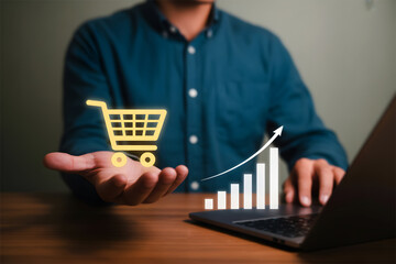 Person holding a shopping cart icon with a bar graph showing increasing sales on a laptop.