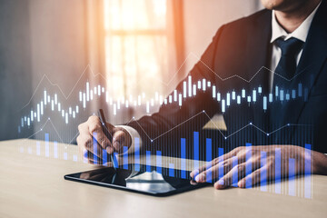A business professional takes notes while analyzing financial charts on a digital tablet, depicting data trends and market insights in a modern work environment. Scalp