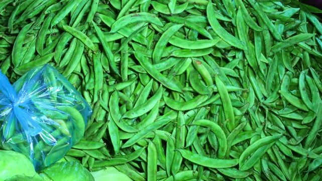 Hyacinth bean pods or sem ki fali are arranged in a pile for sale at a shop, displaying green curved shapes.