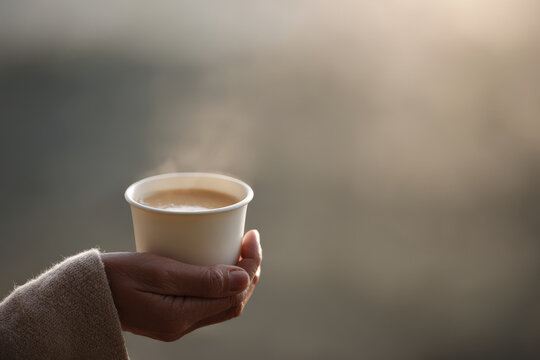 hand gently holds white cup filled with coffee creating warm and inviting atmosphere