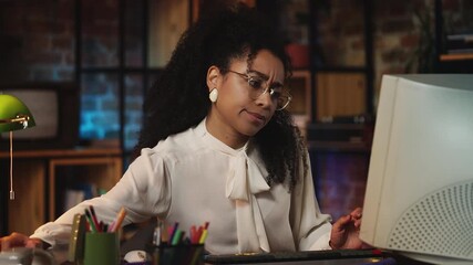 Female office worker in vintage clothes typing on computer and answering phone