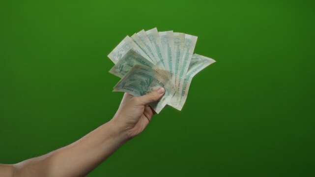 Man holding united arab emirates dirhams against a vibrant green background with a focus on hand and banknotes signifying wealth and finance.