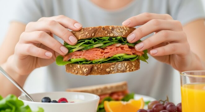 Woman holding a fresh healthy sandwich with salmon and vegetables. Healthy eating and balanced diet for a nutritious lifestyle. - Powered by Adobe