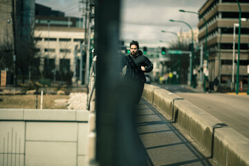 Young adult man jogging on urban bridge, focused and determined