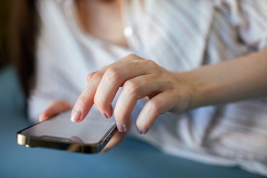 Adult woman tapping smartphone screen at home, focused