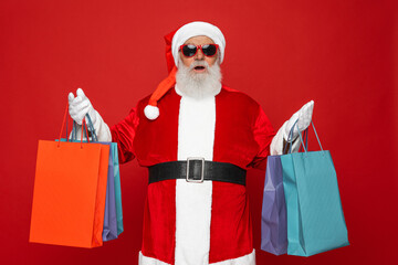 Portrait of his he nice attractive cheerful cheery fat Santa holding in hands carrying things buyings retail store boutique black Friday isolated bright vivid shine vibrant red color background